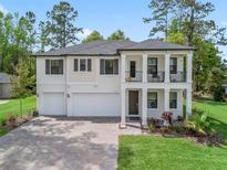 Stately two-story home with a double garage, porch, balcony, manicured lawn, and brick-paved driveway at 3920 Se 7Th Ave, Ocala, FL 34480