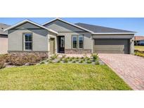 Charming one-story home featuring a stone accent, landscaped yard, and brick driveway leading to an attached garage at 4497 Nw 54Th Ter, Ocala, FL 34482