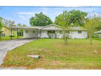 Inviting one-story home featuring a carport, a cozy front porch, and a well-kept lawn at 4516 Ne 8Th St, Ocala, FL 34470