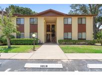 Two-story condo building featuring a beige facade with brown accents, stairs to the second level, and manicured landscaping at 501 Fairways Ln # A, Ocala, FL 34472