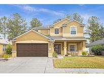Charming two-story home with a well-manicured lawn, large driveway, and a covered front porch with seating at 5781 Sw 39Th St, Ocala, FL 34474