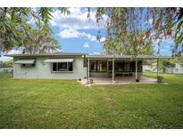 Charming single-story home with a covered patio, lush lawn, and mature trees, offering serene outdoor living at 12180 Maple St, Dunnellon, FL 34432