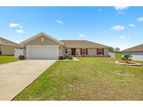 Charming single-story home featuring a well-maintained lawn, attached garage, and red shutters at 15470 Sw 34Th Ave, Ocala, FL 34473