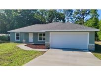 Charming single-story home featuring a neutral color scheme, an attached two-car garage, and a well-maintained lawn at 19920 Sw Eagle Dr, Dunnellon, FL 34431