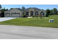 Charming single-story home with a well-manicured lawn and a three-car garage, set against a blue sky at 5323 Sw 111Th Lane Rd, Ocala, FL 34476