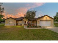 Charming single-story home with a well-manicured lawn and attached two-car garage at sunset at 6701 Nw 6Th Ave, Ocala, FL 34475