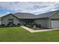 Attractive single-story home featuring a well-kept lawn, landscaped garden, and an attached two-car garage at 9188 Se 150Th St, Summerfield, FL 34491