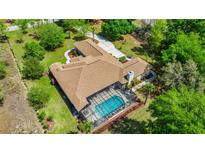 Expansive aerial view of a home with a screened-in pool and well-maintained landscaping at 18498 Sw 69Th Loop, Dunnellon, FL 34432