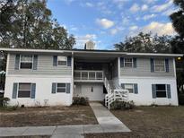 Two-story exterior with white and gray siding and blue shutters; covered balconies and stairs lead to upper units at 8232 Fairways Cir # D101, Ocala, FL 34472