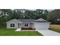 Charming single-story home with a gray exterior, a well-manicured lawn, and an attached two-car garage at 27 Juniper Pass Way, Ocala, FL 34480