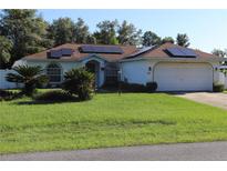 Well maintained single story home featuring solar panels, a lush lawn, and a two car garage at 4413 Sw 145Th Place Rd, Ocala, FL 34473