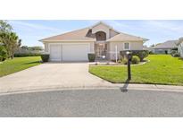 Charming one-story home with a well-maintained lawn, two-car garage, and beautifully manicured shrubs at 17645 Se 117Th Cir, Summerfield, FL 34491