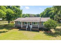 Charming single-story home with a covered front porch, green shutters, and a spacious green lawn at 2720 Se 145Th St, Summerfield, FL 34491