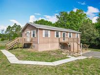 Charming two-story home featuring a wooden deck, walkway, and lovely landscaping against a blue sky at 2800 Sw 141St Ct, Ocala, FL 34481