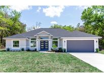 Beautiful home featuring a manicured lawn, gray paint, and a matching garage door at 8878 Sw 133Rd Lane Rd, Ocala, FL 34473