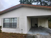 Home exterior shows window detail and a single parking carport on a cloudy day at 32 Spring Loop Circle, Ocala, FL 34472