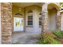 Inviting front entrance with decorative glass door, stone pillar accents, and covered porch at 4780 Sw 103Rd Street Rd, Ocala, FL 34476