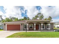 Charming single-story home featuring a brick-paved walkway, attached garage, and inviting front porch with columns at 5026 Sw 128Th St, Ocala, FL 34473