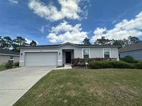 Charming single-story home featuring a well-manicured lawn, gray exterior and a two-car garage at 593 Marion Oaks Trl, Ocala, FL 34473