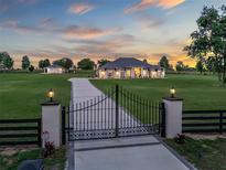 Gated estate showcasing a long driveway leading to an elegant home at sunset at 7161 Ne 22Nd Court Rd, Ocala, FL 34479