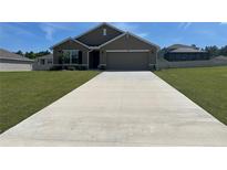 Charming single-story home with a well-manicured lawn and a long driveway leading to a two-car garage at 7198 Sw 136Th Street Rd, Ocala, FL 34473
