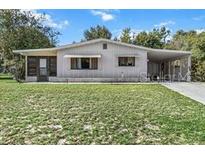 Charming single-story home with covered carport and well-maintained lawn, nestled among mature trees at 8954 Sw 104Th Ln, Ocala, FL 34481