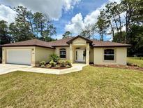 Charming single-story home featuring a well-manicured lawn, fresh landscaping, and an attached two-car garage at 19939 Sw 96Th Pl, Dunnellon, FL 34432