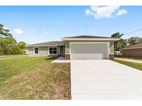 Charming single-story home featuring a well-manicured lawn and a spacious two-car garage at 207 Juniper Loop Cir, Ocala, FL 34480