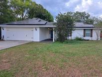 Charming single-Gathering home featuring a two-car garage and solar panels on the roof at 33 Pecan Pass Trl, Ocala, FL 34472