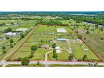 Expansive aerial view of a horse farm with paddocks, barns, riding arena, and residence, all within a clearly defined perimeter at 5415 Nw 100Th St, Ocala, FL 34482