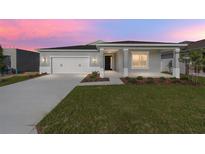 Charming single-story home featuring a two-car garage, covered porch, and well-manicured lawn at dusk at 5714 Sw 75Th Ave, Ocala, FL 34474