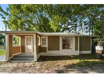 Charming single-story home with brown siding, a covered porch, and a mature tree in the front yard at 935 Ne Sanchez Ave, Ocala, FL 34470