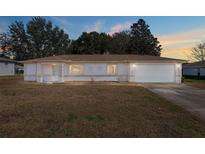 Charming home featuring a two-car garage and well-kept lawn at dusk at 10141 Sw 62Nd Terrace Rd, Ocala, FL 34476
