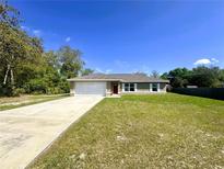 Charming single-story home with a well-maintained lawn, attached garage, and a welcoming red door at 15585 Sw 46Th Cir, Ocala, FL 34473