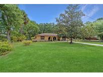 Charming single-story home with mature trees, a well-manicured lawn, and lush landscaping at 16405 Se 90Th Ct, Summerfield, FL 34491