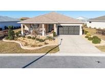 Charming home featuring manicured landscaping, a covered front porch, and a two-car garage at 8878 Sw 103Rd Cir, Ocala, FL 34481