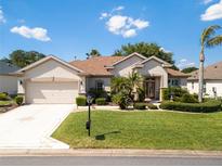 Charming home featuring a well-manicured lawn, beautiful landscaping, and an inviting front entrance at 9347 Se 137Th Street Rd, Summerfield, FL 34491