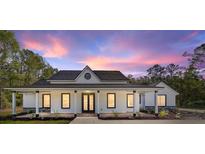 Beautiful single-story home featuring a covered porch and landscaped front yard against a stunning sunset backdrop at 14115 Nw 141St Ave, Williston, FL 32696