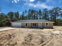 Charming single-story home with a large front yard and attached two-car garage in a wooded area at 22764 Sw Sea Cliff Ave, Dunnellon, FL 34431