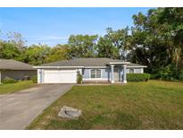 Charming single-story home with manicured lawn, blue exterior, and attached two-car garage at 2199 Se 175Th Ter, Silver Springs, FL 34488