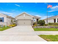 Charming home featuring a well-manicured lawn, a two-car garage, and an American flag at 5220 Sunshine Dr, Wildwood, FL 34785