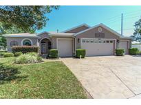 Beautiful single-story home with three-car garage, lovely landscaping, and stamped driveway at 1213 Meadowbend Dr, Leesburg, FL 34748