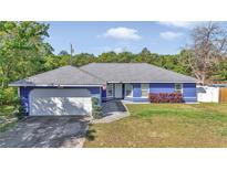 Charming single-story home with a well-maintained lawn, gray roof, and a two-car garage at 13800 Sw 33Rd Court Rd, Ocala, FL 34473