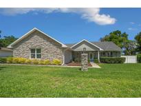 Charming single-story home featuring a stone facade, lush green lawn, and well-manicured landscaping at 4401 Sw 44Th Ln, Ocala, FL 34474