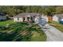 Charming single-Gathering home featuring a manicured lawn and an attached two-car garage at 5900 Nw 61St Ct, Ocala, FL 34482