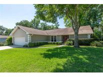 Charming single-story home with a well-manicured lawn, lush landscaping, and inviting red front door at 8120 Nw 48Th Ln, Ocala, FL 34482