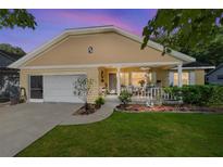 Dusk view of a charming home featuring a covered front porch, attached garage, and lush lawn at 9153 Sw 83Rd Ter # E, Ocala, FL 34481