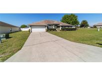 Inviting single-story home featuring a well-maintained lawn, mature shrubbery, and a convenient two-car garage at 9896 Sw 56Th Ct, Ocala, FL 34476