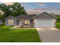 Charming single-story home with a well-manicured lawn and a two-car garage under a picturesque sunset at 12 Oak Circle Pass, Ocala, FL 34472