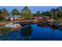 Beautiful waterfront home featuring two houses with a large dock and an inviting pontoon boat at 23800 Ne 190Th St, Fort Mc Coy, FL 32134